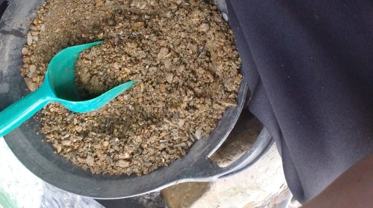A bucket of classified gravel and a scoop beside a Lowther Hills burn — a working UK prospecting kit.