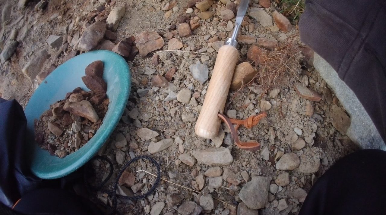 A gold pan and trowel on the gravel of a Lowther Hills burn — the two tools you need to start.