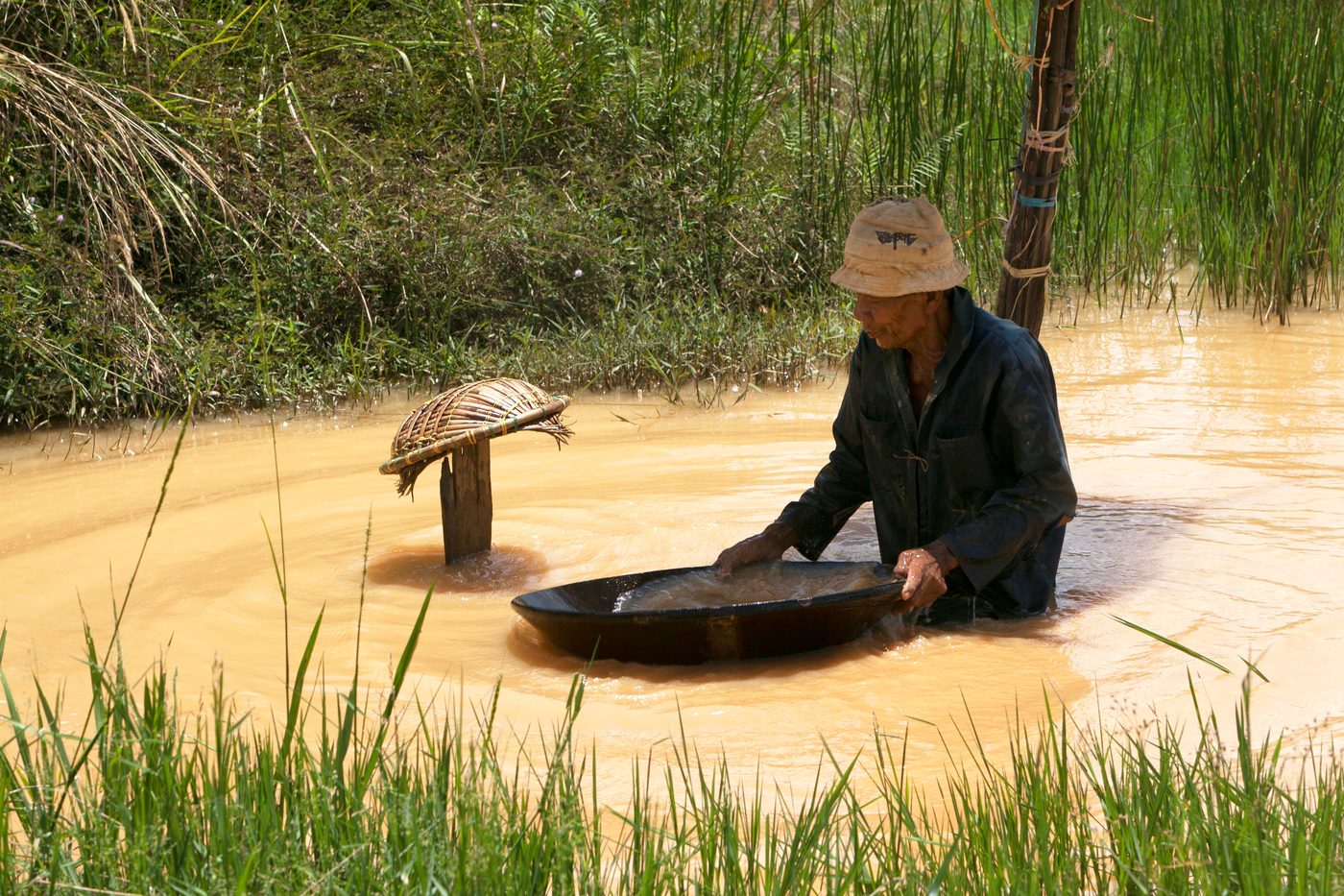A prospector panning gold by hand in a shallow Scottish burn, the kind of fine-flake hand panning done at the Kildonan Burn near Helmsdale.